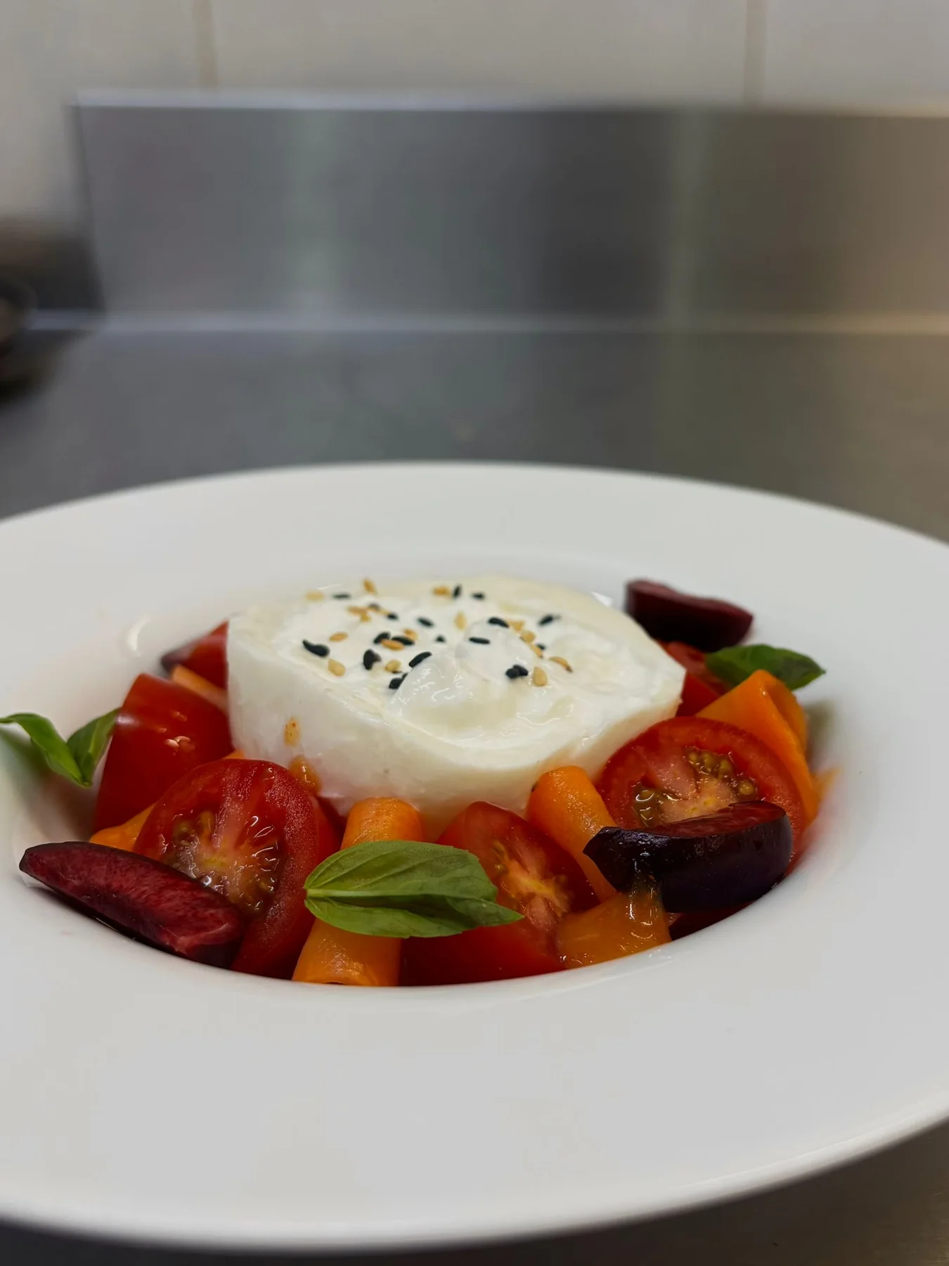 Burrata, fermented carrot, cherry tomatoes, plum, carrot and truffle sauce, sesame, basil.